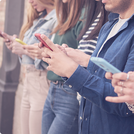 Skupina ľudí píše správy na mobiloch, služba hromadného rozosielania SMS.