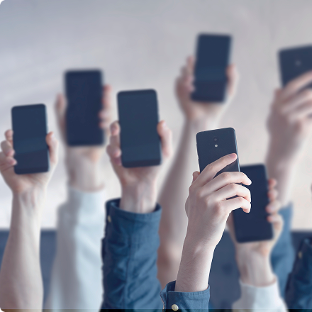 Zdvihnuté ruky s mobilnými telefónmi v pracovnom prostredí.